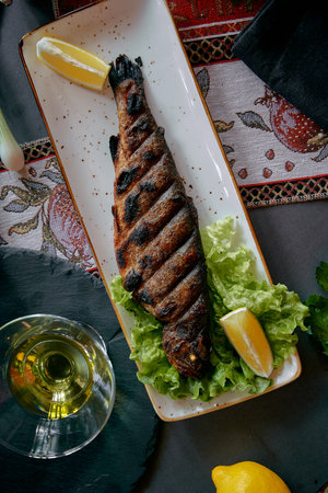 Grilled Fish Served on a Plate with Fresh Lettuce and Lemon Slices, Accompanied by Olive Oil for a Deliciously Healthy Meal Presentationの写真素材