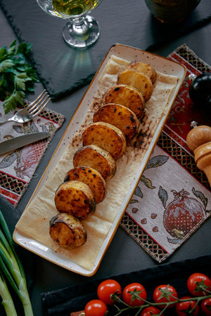 Deliciously Grilled Potatoes Served on a Rectangular Plate with Fresh Garnishes and Accompaniments for a Flavorful Culinary Experienceの写真素材
