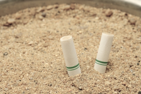 Close-up cigarette butts in the sand の写真素材
