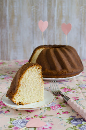 Homemade delicious cream cake on the whipped cream on the delicate pink tablecloths flowered to celebrate loversの写真素材