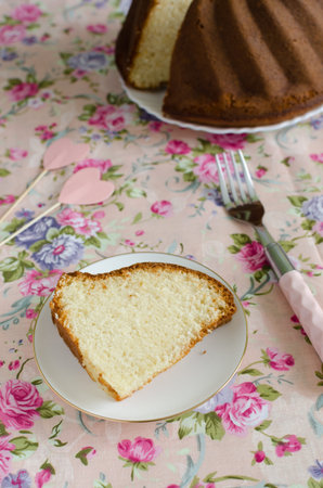 Homemade delicious cream cake on the whipped cream on the delicate pink tablecloths flowered to celebrate loversの写真素材