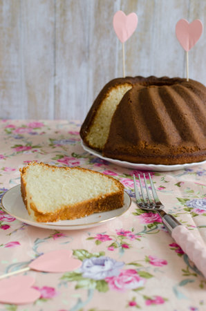 Homemade delicious cream cake on the whipped cream on the delicate pink tablecloths flowered to celebrate loversの写真素材