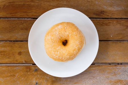Sweet donut in the white dish on the wood table.