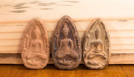 Small buddha image used as amulets on wood background.の写真素材