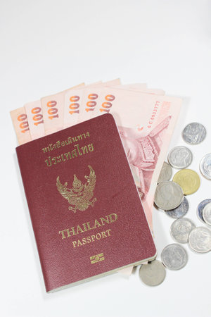 Thai passport book with money and coins isolated on white backgroundの写真素材
