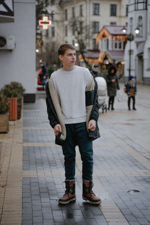 a teenager in winter clothes in full growth looks to the side, winter time in europe without snowの写真素材