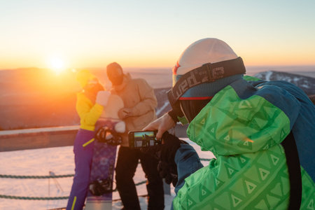 freezes the moment on a mobile phone, on a mountain during sunset, winter landscape, a good time outdoorsの写真素材