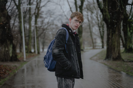 wet snow, rainy winter outside, cloudy weather, a stylish young man with curly hair and round...