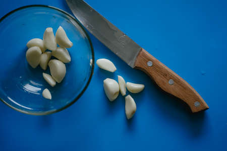 anti-virus vitamins, peeled garlic, cooking, a knife and garlic are on a blue boardの写真素材