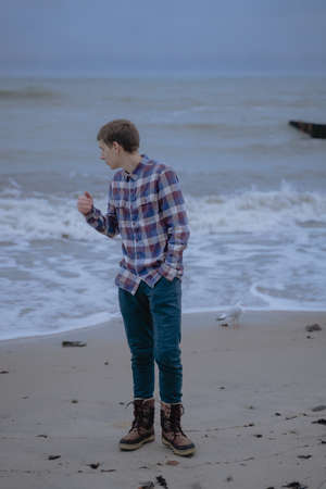 teenager in a plaid shirt against the background of the sea looks thoughtfully asideの写真素材