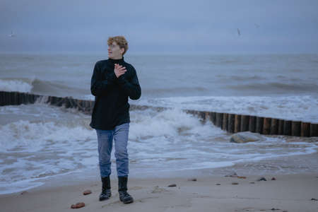 smiling guy in a black jacket on the background of the sea looks to the sideの写真素材