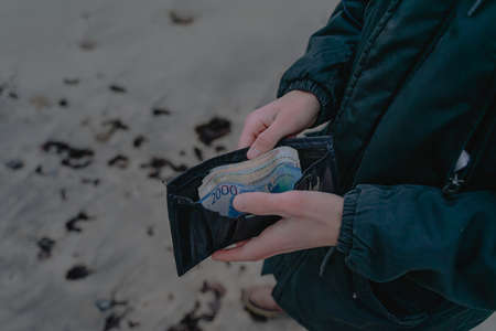 paper money lies in a wallet, he holds a purse with finances in his handsの写真素材