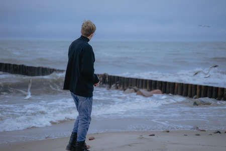 lonely guy meditates on the shores of the rough seaの写真素材