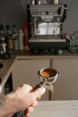 holds a holder with a tempered coffee tablet against the background of a coffee machine, a mini cafe...