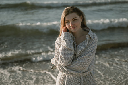 portrait of a cute girl against the backdrop of sea waves, looking at the camera smilingの写真素材