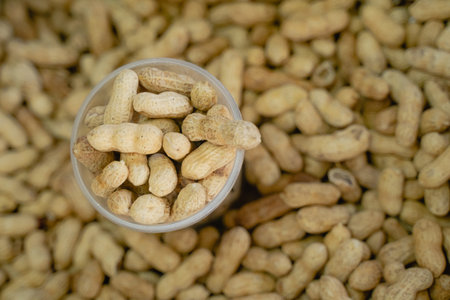 shelled peanuts lie in a glass, top view a lot of unpeeled peanuts