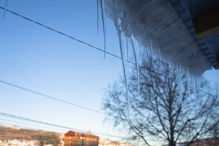 ice icicles hang from the roof of the house, spring dropsの写真素材