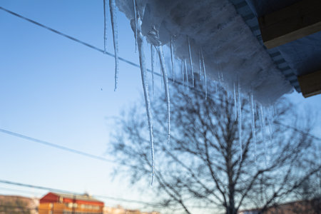 ice icicles hang from the roof of the house, spring dropsの写真素材