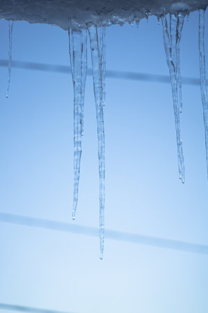 melting ice icicles hanging from the roofの写真素材