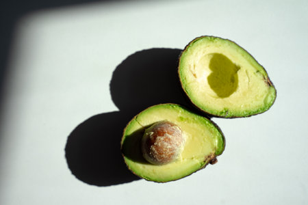 cut avocado lies on the table, bright sunlight falls on the avocadoの写真素材