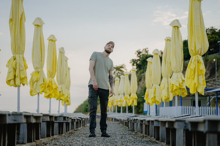 man standing in sun loungers with yellow parasolsの写真素材
