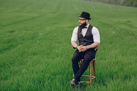 lone bearded man who looks like a millionaire standing in fieldの写真素材