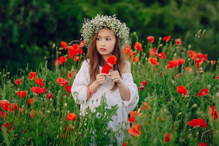 beautiful little girl in a wreath of poppiesの写真素材