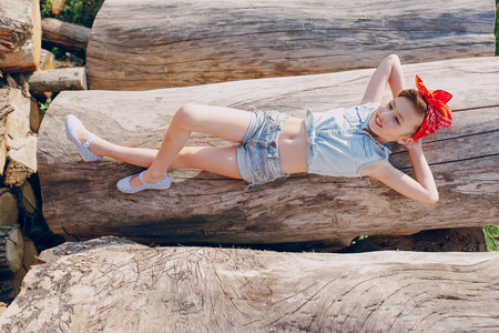 little girl sitting on the wood style pin up in jeans clothesの写真素材