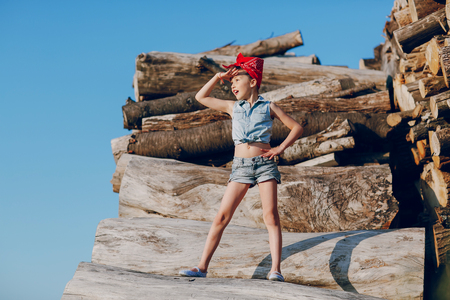 little girl sitting on the wood style pin up in jeans clothesの写真素材