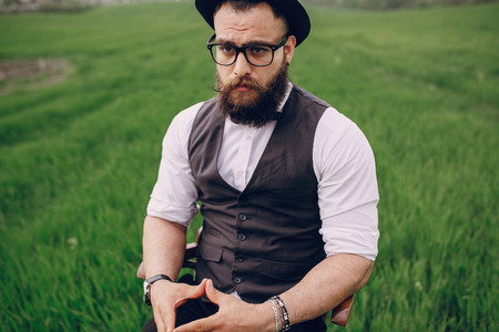 lone bearded man who looks like a millionaire standing in fieldの写真素材