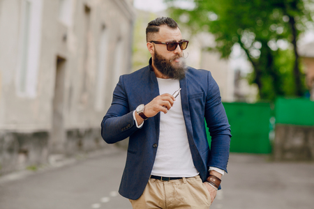 bearded man with e-cigarette outdoors on summer dayの写真素材