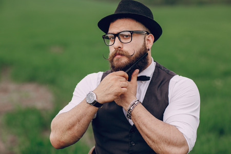 lone bearded man caring for his beard in the fieldの写真素材