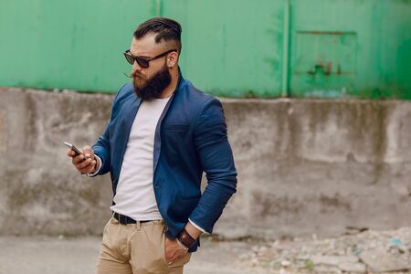 beard man with phone syanding on summer dayの写真素材