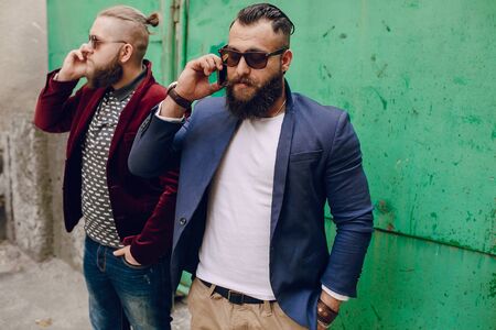 Two bearded men use mobile phones outdoorsの写真素材