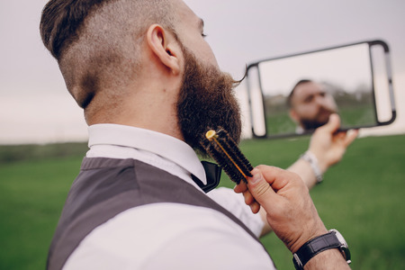 lone bearded man caring for his beard in the fieldの写真素材