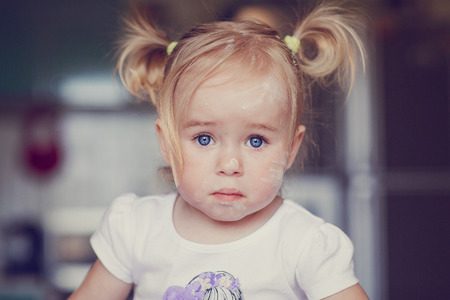 beautiful little girl learns to cook a meal in the kitchenの写真素材