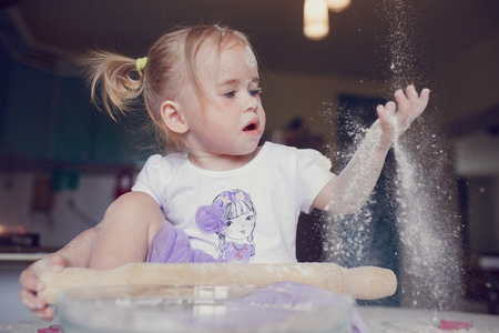 beautiful little girl learns to cook a meal in the kitchenの写真素材