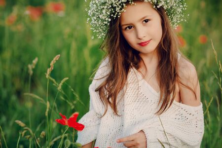 beautiful little girl in a wreath of poppiesの写真素材
