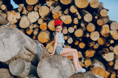 little girl sitting on the wood style pin up in jeans clothesの写真素材