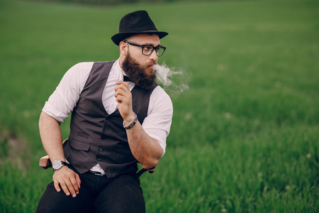 lone bearded man enjoys in the field of e-cigaretteの写真素材
