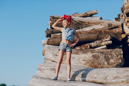 little girl sitting on the wood style pin up in jeans clothesの写真素材