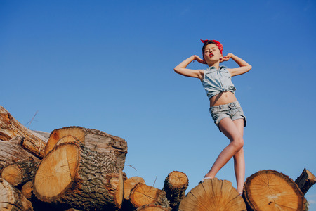 little girl sitting on the wood style pin up in jeans clothesの写真素材