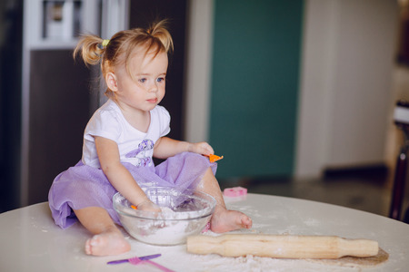 beautiful little girl learns to cook a meal in the kitchenの写真素材