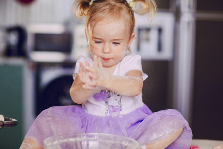 beautiful little girl learns to cook a meal in the kitchenの写真素材