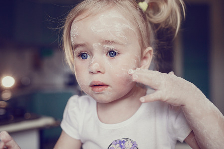 beautiful little girl learns to cook a meal in the kitchenの写真素材