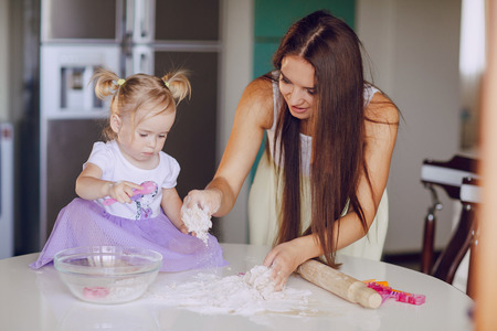 young beautiful mother teaches daughter prepare dough in the kitchenの写真素材