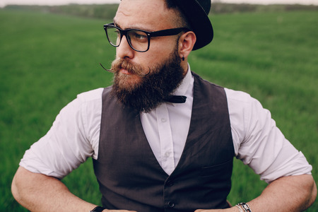 lone bearded man who looks like a millionaire standing in fieldの写真素材