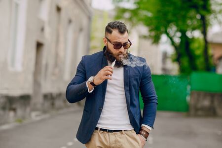 bearded man with e-cigarette outdoors on summer dayの写真素材