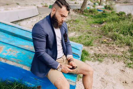 bearded man on the boat with phone summer dayの写真素材