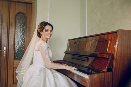 beautiful bride is sitting at the pianoの写真素材
